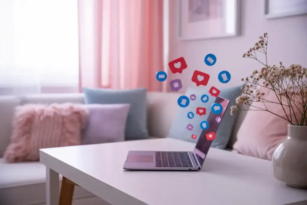 pink and blue home office with an open laptop on a small table with social media icons floating out of it.