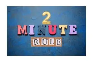 Colorful block letters spelling out '2 MINUTE RULE' on a textured blue background, emphasizing the productivity technique